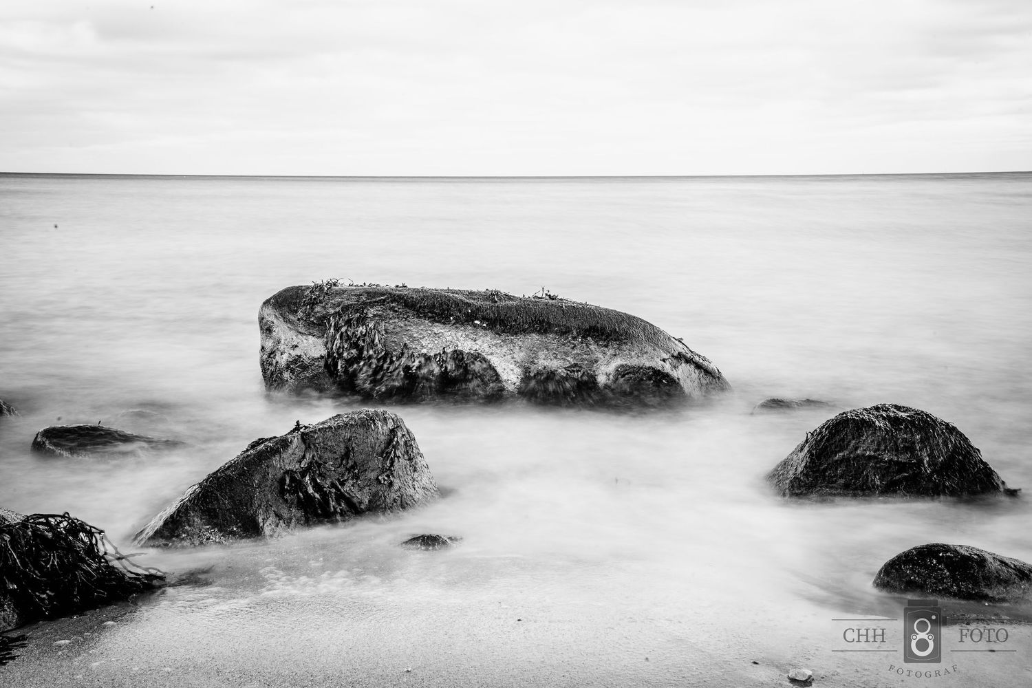 Sort-hvid naturfotografi med sten og blødt vand – minimalistisk fotokunst og plakat til væggen.