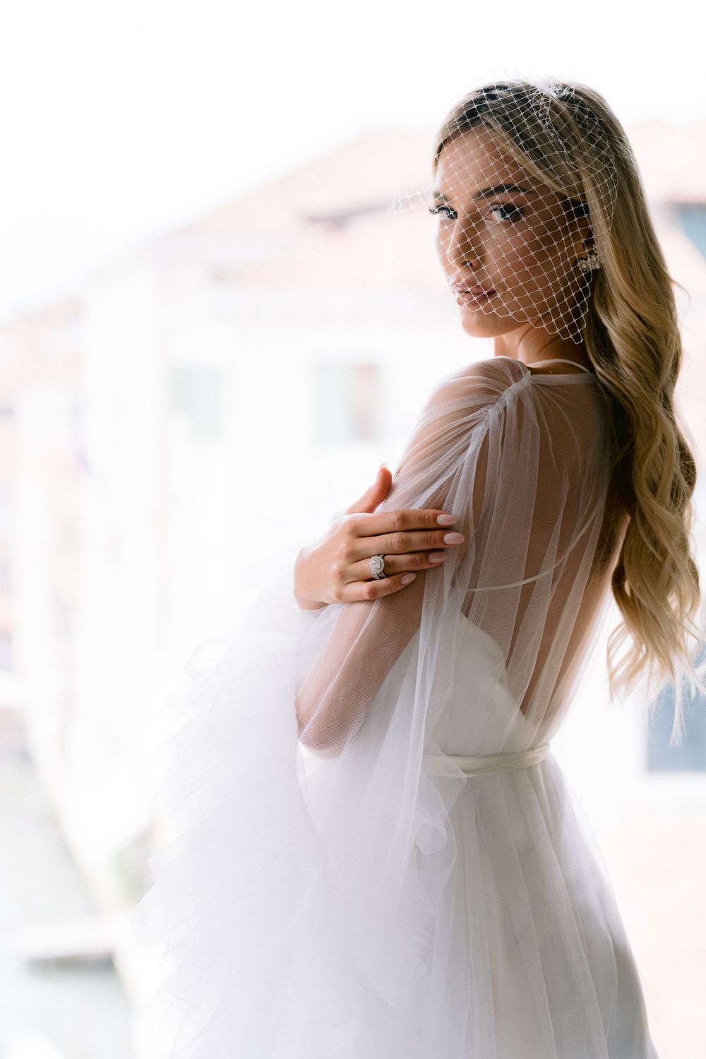 Dreamy bridal portraits with soft focus showing flowing white dress and natural window light.