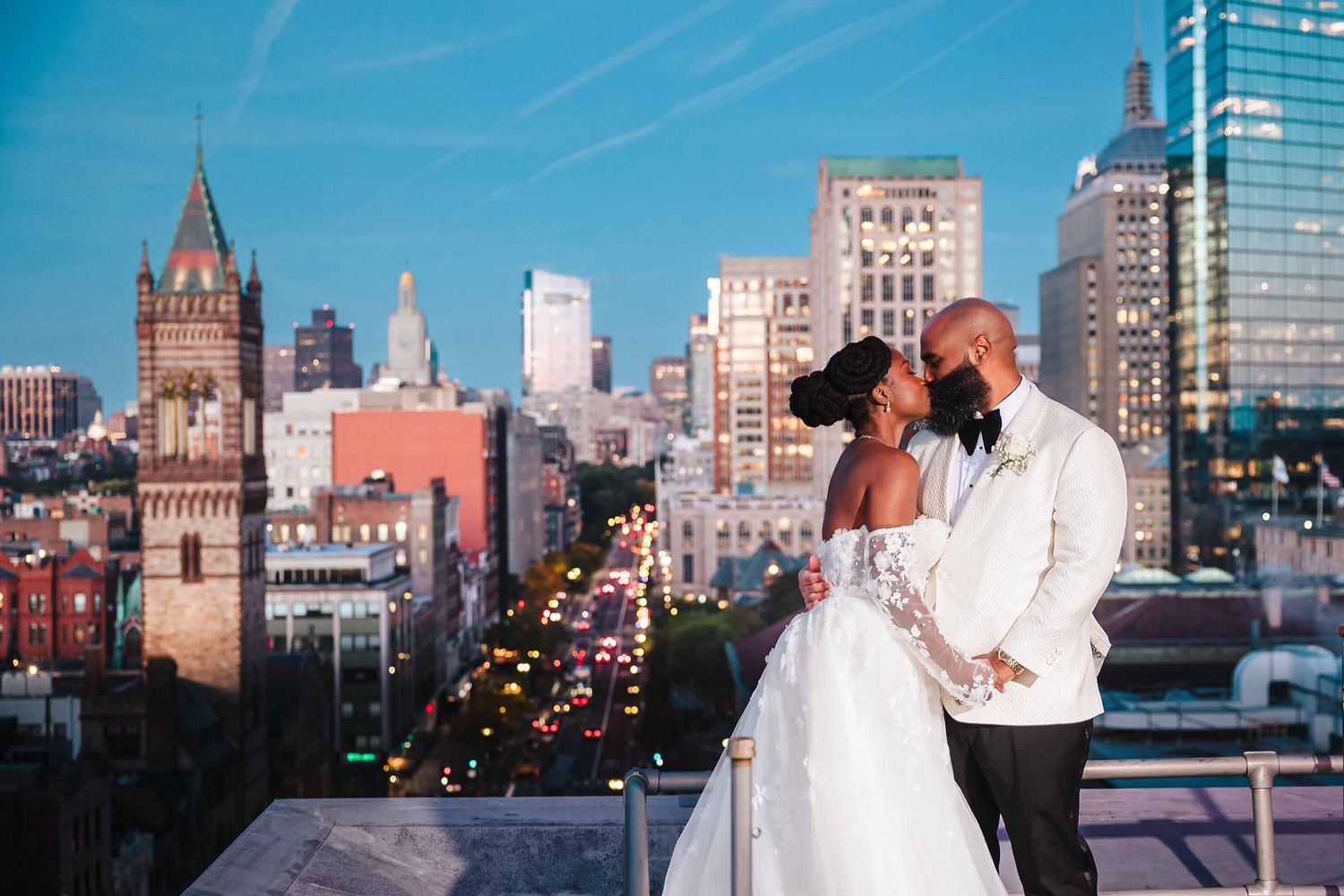 Bride and groom kissing at sunset on the Hotel Lenox rooftop overlooking the Boston skyline, portrait by a Boston wedding photographer