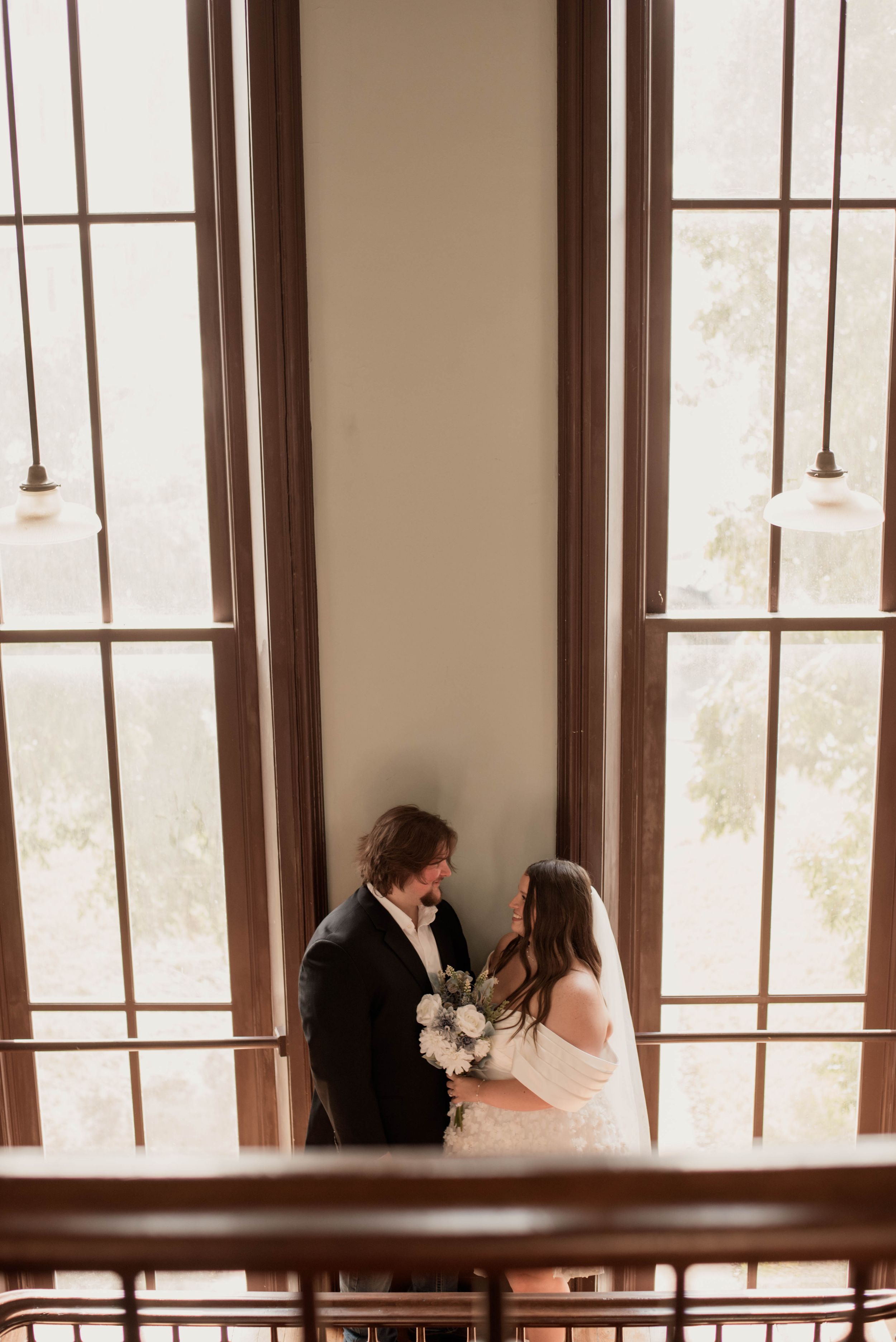 Bride and groom share a quiet moment on a balcony inside the historic Weatherford Courthouse.