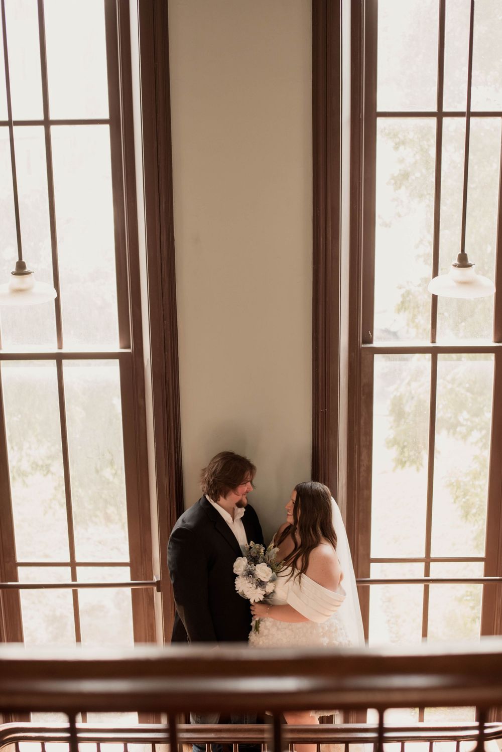 Bride and groom share a quiet moment on a balcony inside the historic Weatherford Courthouse.