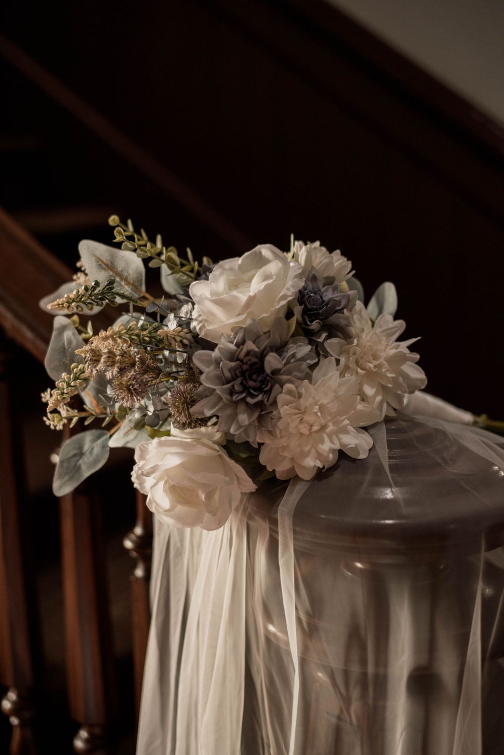 White rose and blue thistle wedding bouquet with ivory ribbons displayed on the staircase inside the Weatherford Courthouse.