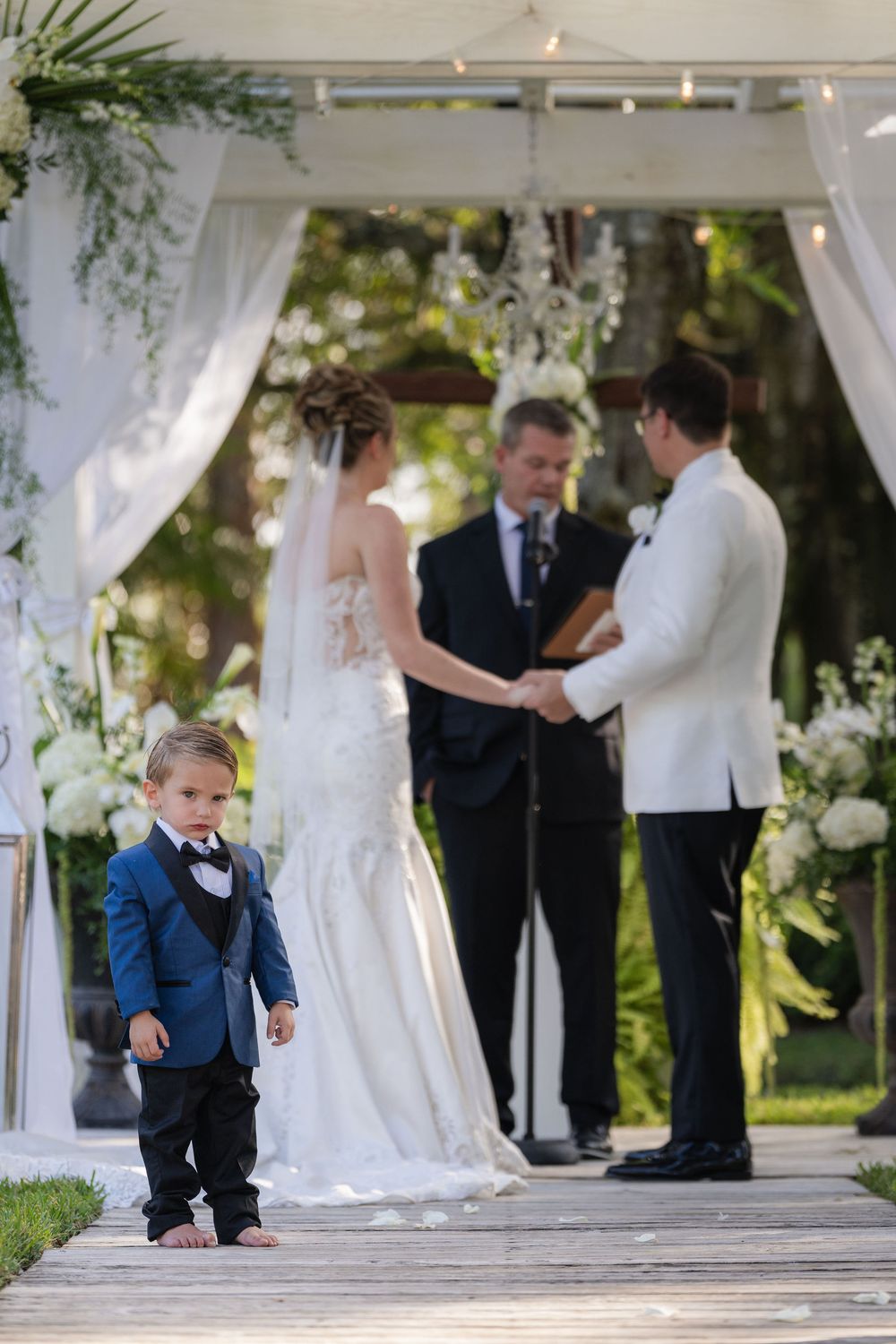 Ring bearer looking unamused as the couple exchanges vows at Magnolia Manor, Vero Beach, FL