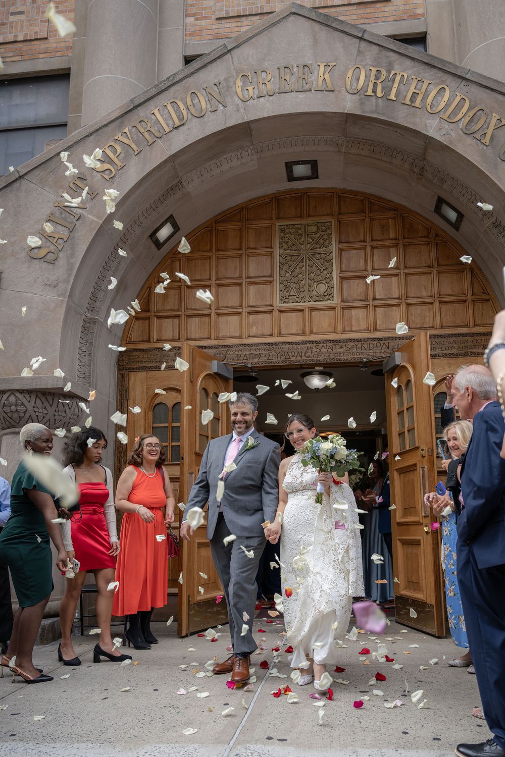 Newlyweds exiting through flower petals at St. Spyridon Greek Orthodox Church, New York, NY