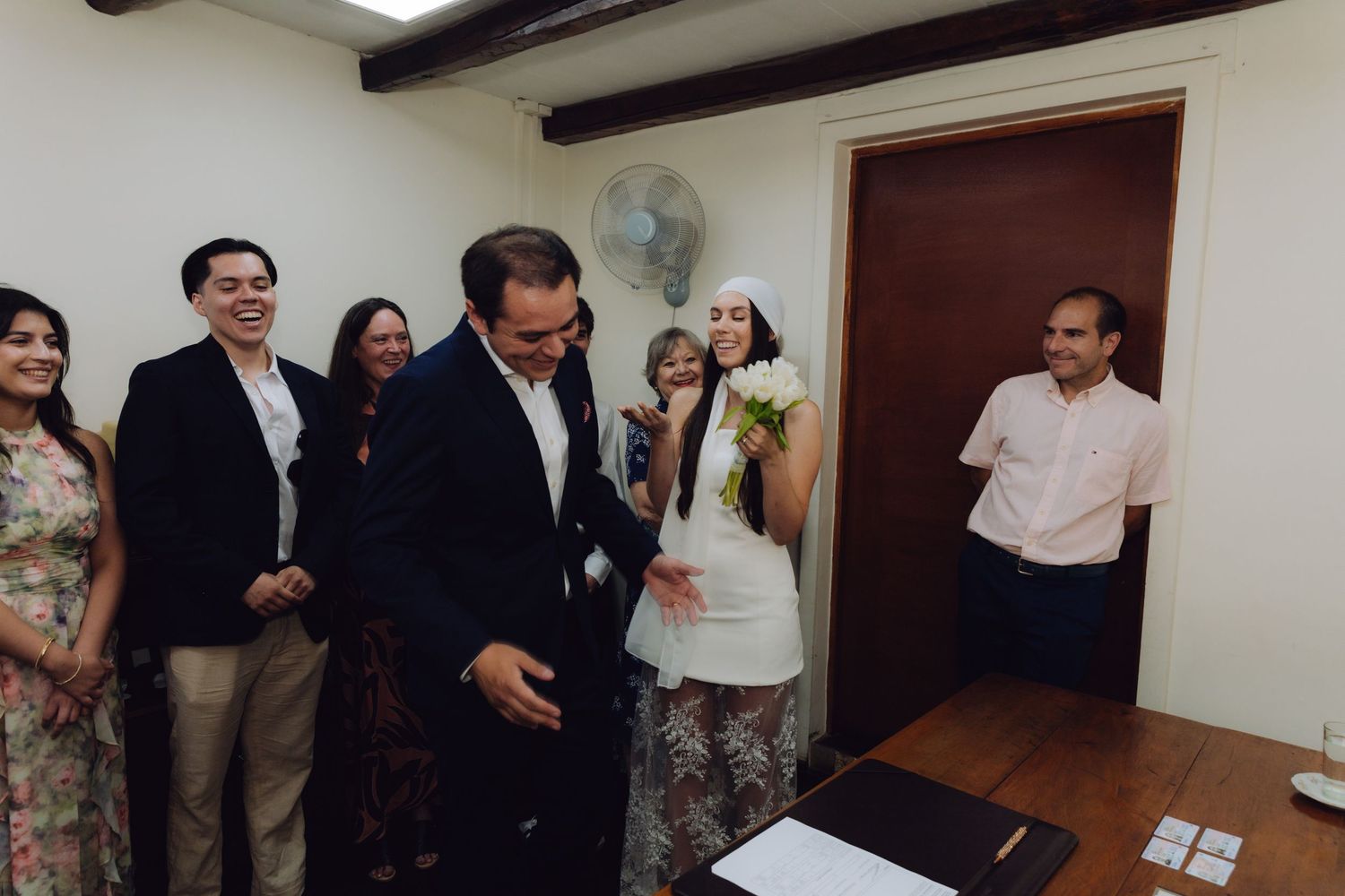 Guests laugh and celebrate during an intimate civil wedding ceremony indoors.