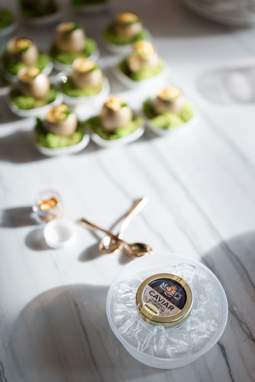 Gourmet appetizers and caviar on marble surface with elegant dining accessories.