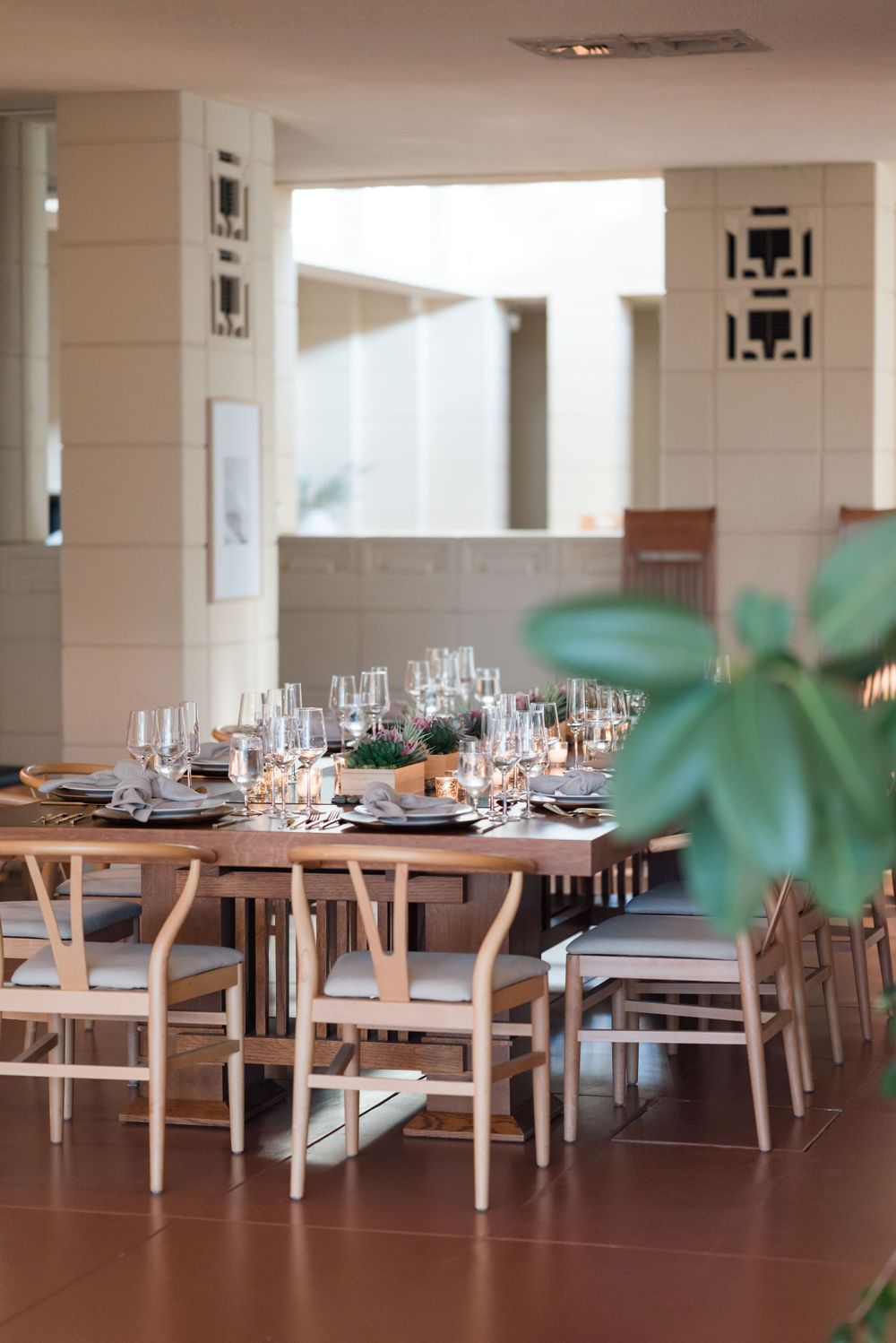 Modern dining room setup with wooden chairs and elegant table settings in a bright, airy space.