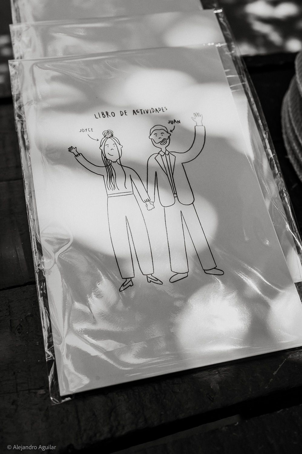 Black and white photo of a wedding activity book cover featuring a cartoon couple holding hands, labeled Libro de Actividades.