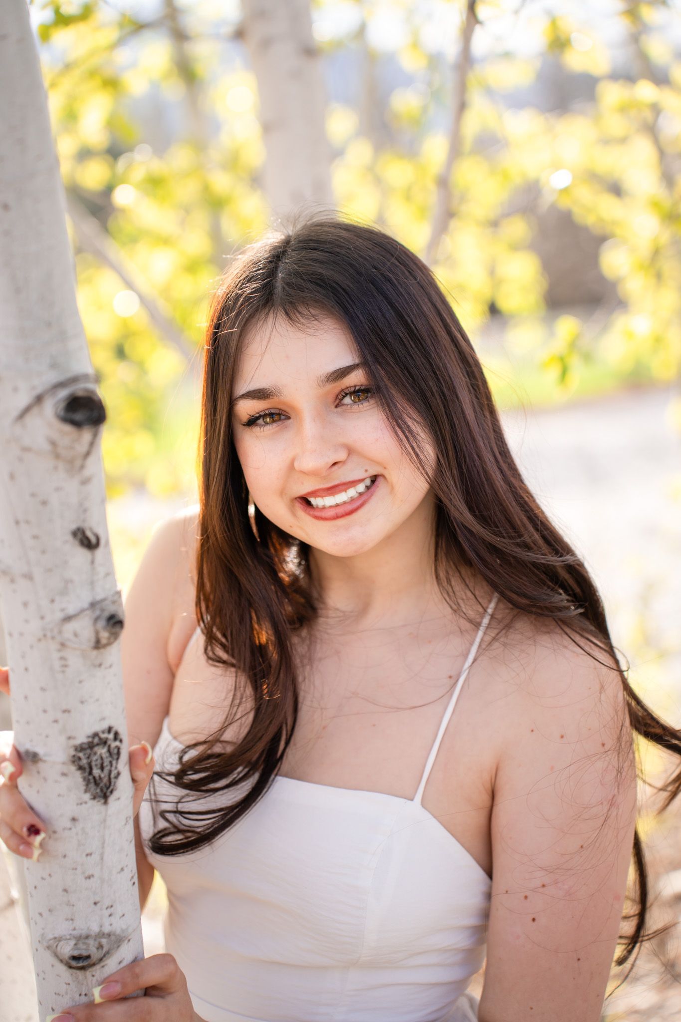 senior portrait of a girl by a tree with white bark and yellow leaves