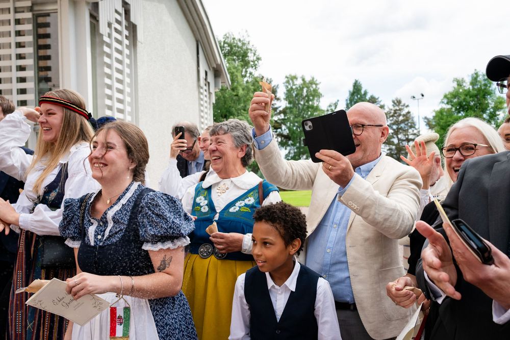 People in traditional Scandinavian folk costumes celebrating outdoors, smiling and taking selfies at a festive cultural event.