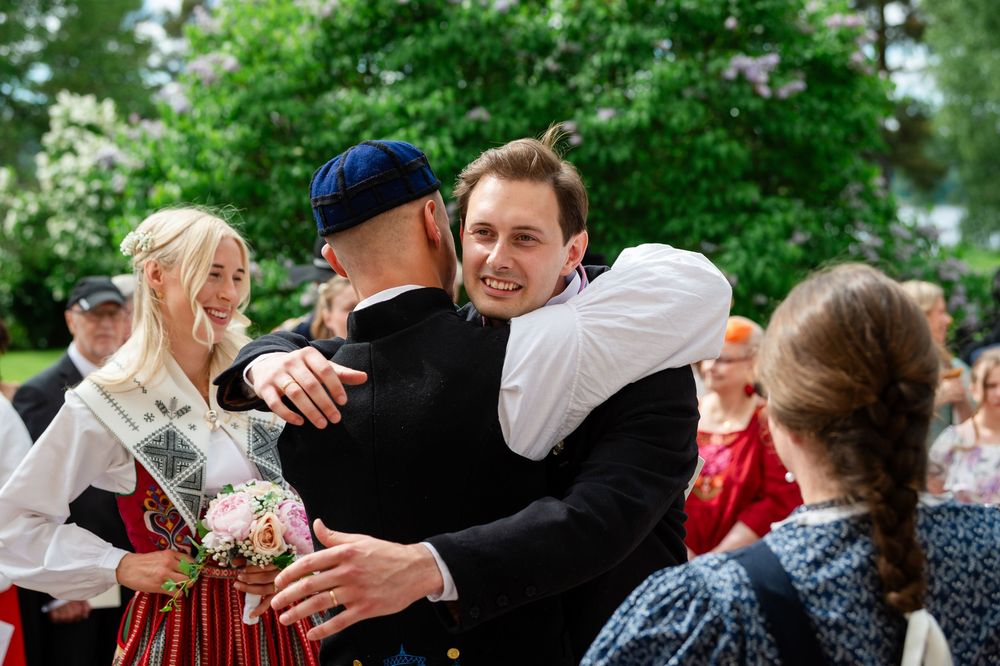 People in traditional Scandinavian folk costumes hugging and celebrating outdoors at a festive cultural event.