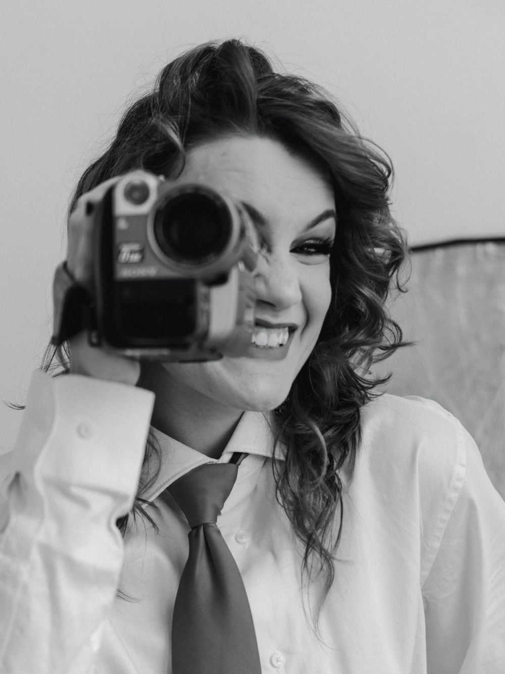 Woman wearing a button down shirt & tie while holding a vintage tape recorder