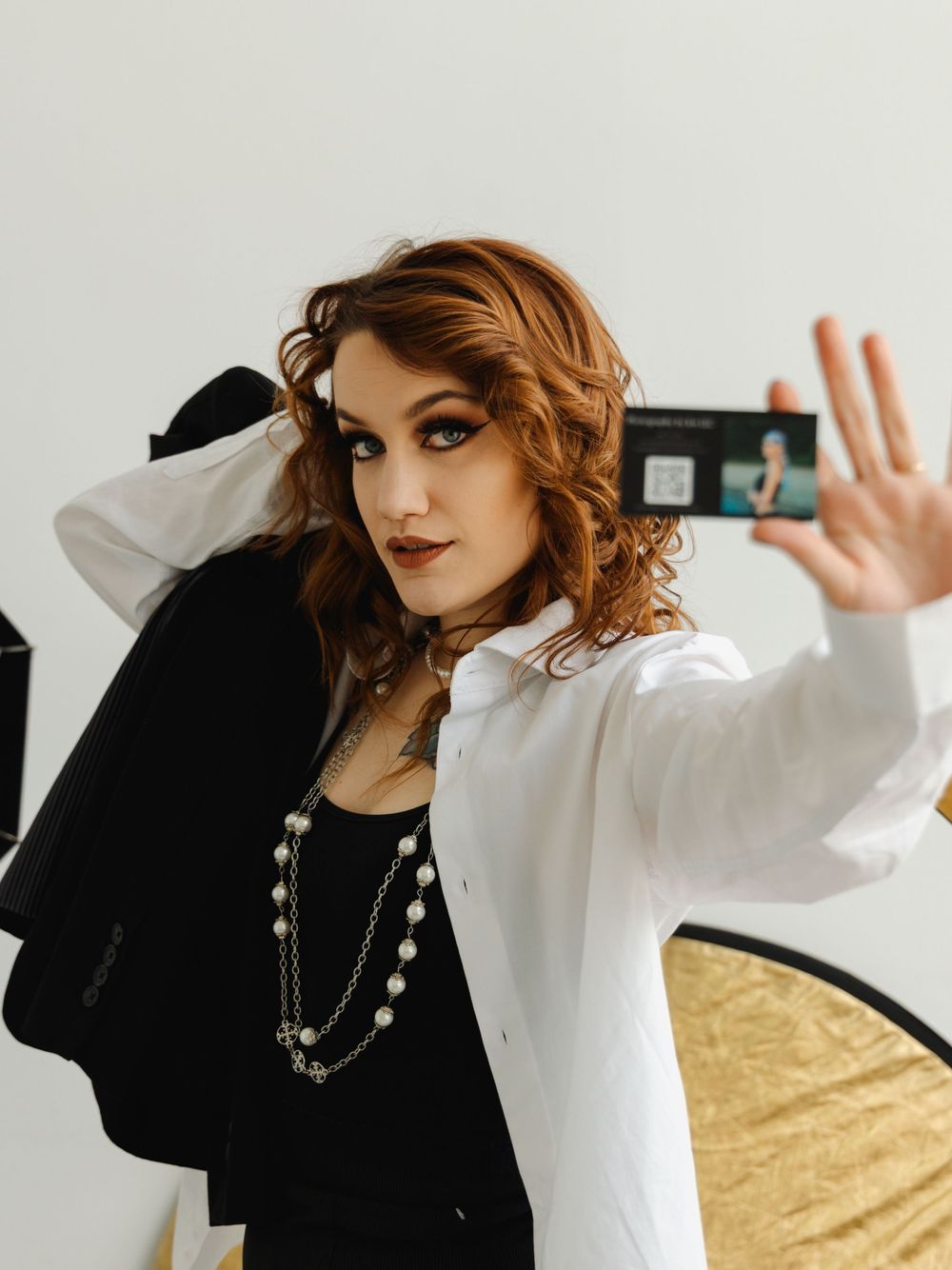 Photographer wearing business attire holding a business card near her face
