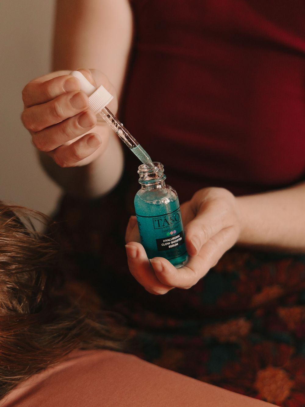 Esthetician holding a dropper & bottle of blue face serum