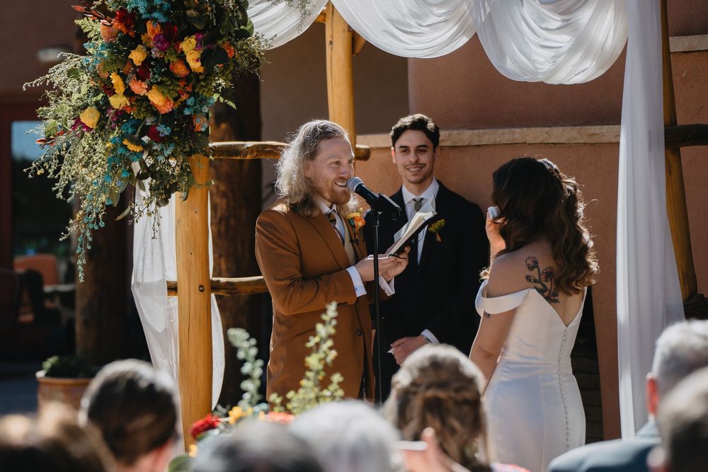 Officiant reads at rustic wooden altar as bride and groom exchange vows outdoors at Nature Pointe Venue