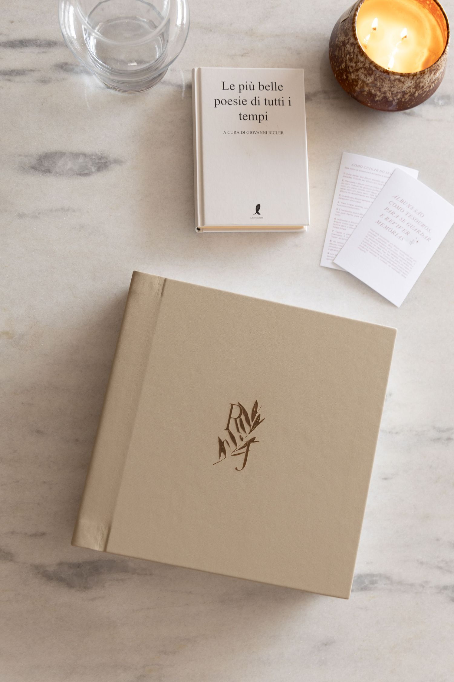 Open wedding photo album displaying black and white ceremony images on marble surface with orange box.
