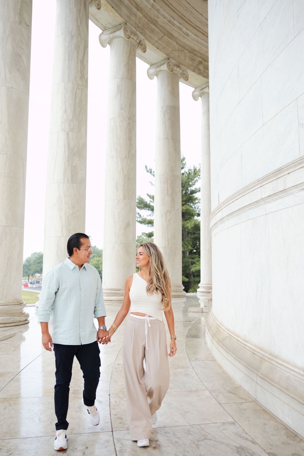 Couple holding hands and walking among tall marble columns at the Jefferson Memorial in Washington D.C.