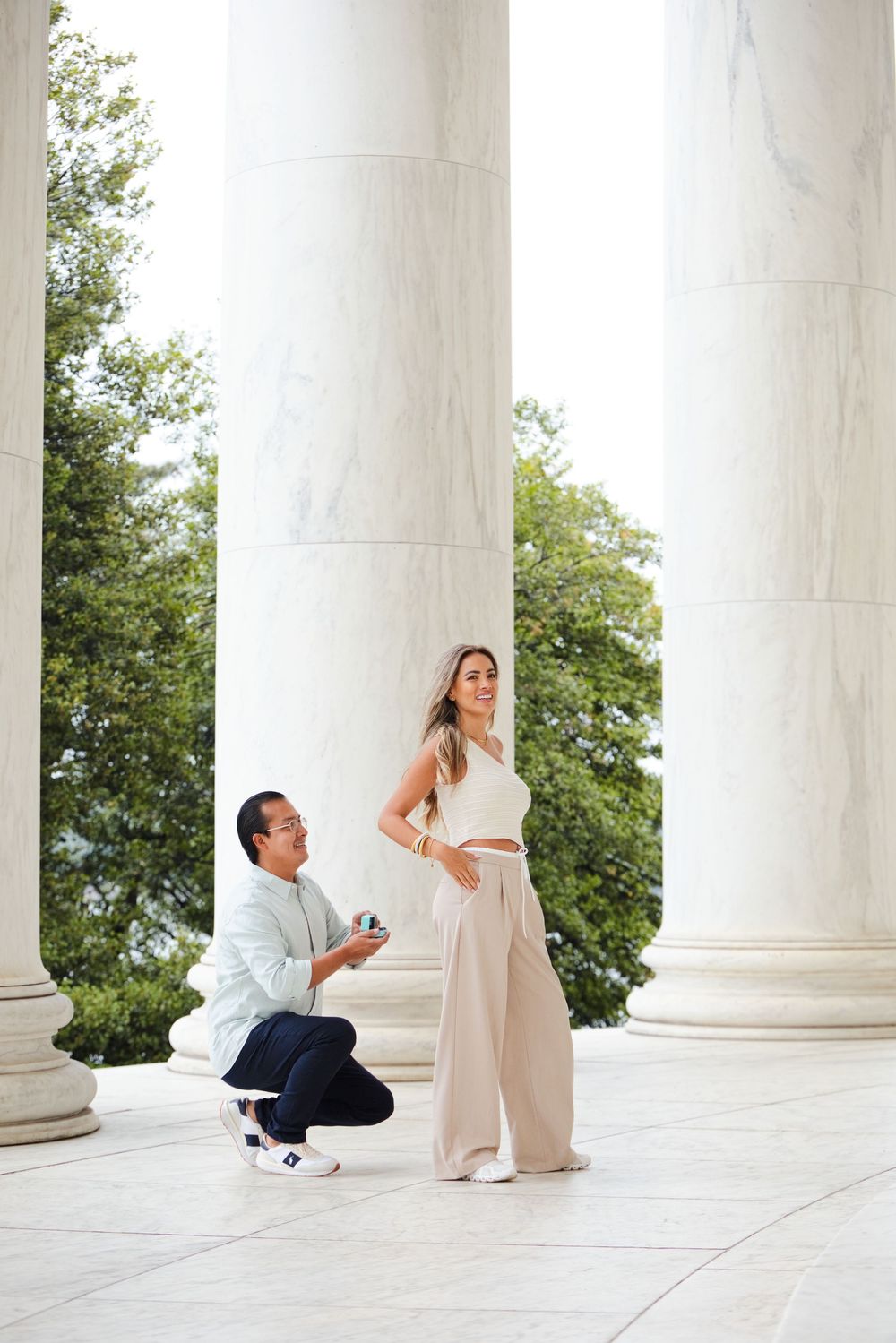 Man proposing to woman at Jefferson Memorial, surrounded by marble columns, in Washington D.C.