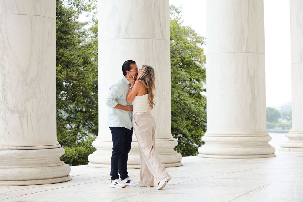 Couple sharing a romantic kiss between marble columns at the Jefferson Memorial in Washington DC.