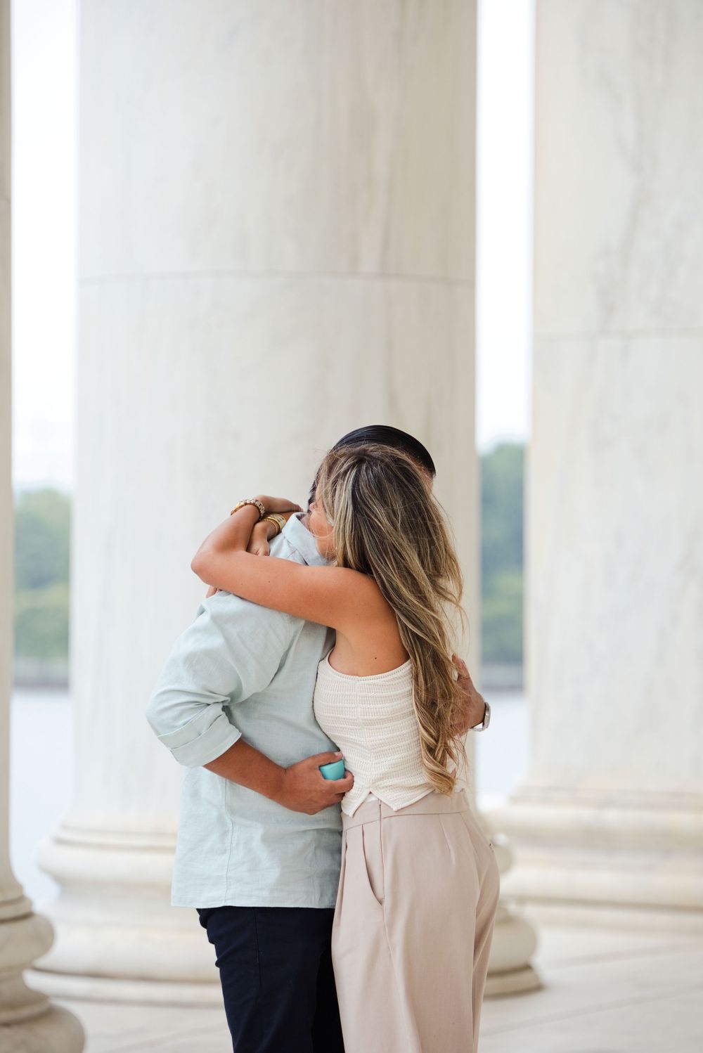 Couple embracing romantically between marble columns at the Jefferson Memorial in Washington DC.