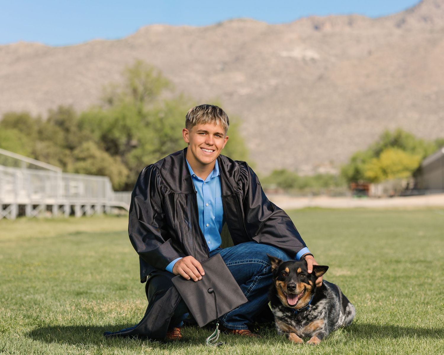 High school senior guy on a football field in Tucson with his dog, photographed by Tucson Senior Photographer