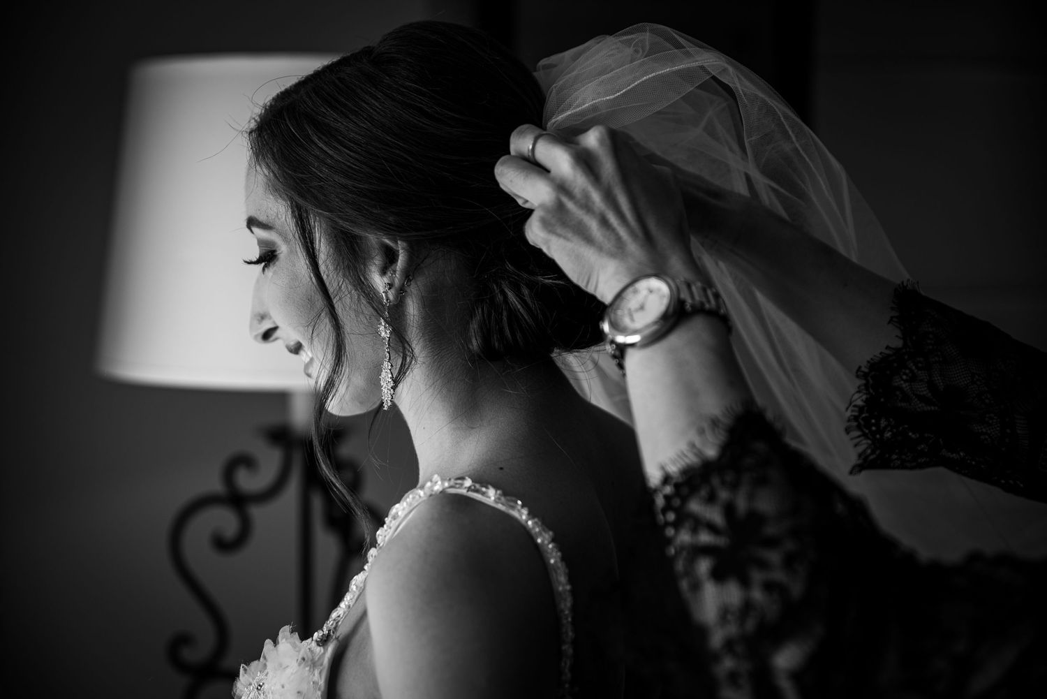 Black and white bridal portrait of a bride in veil smelling white rose bouquet, eyes closed, elegant wedding photography.