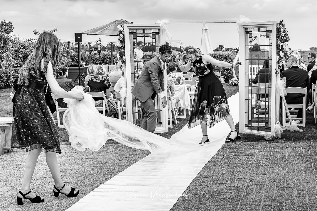 Zwart-wit foto van de laatste voorbereidingen: de beschermlaag wordt van de witte loper gehaald vlak voor de ceremonie
