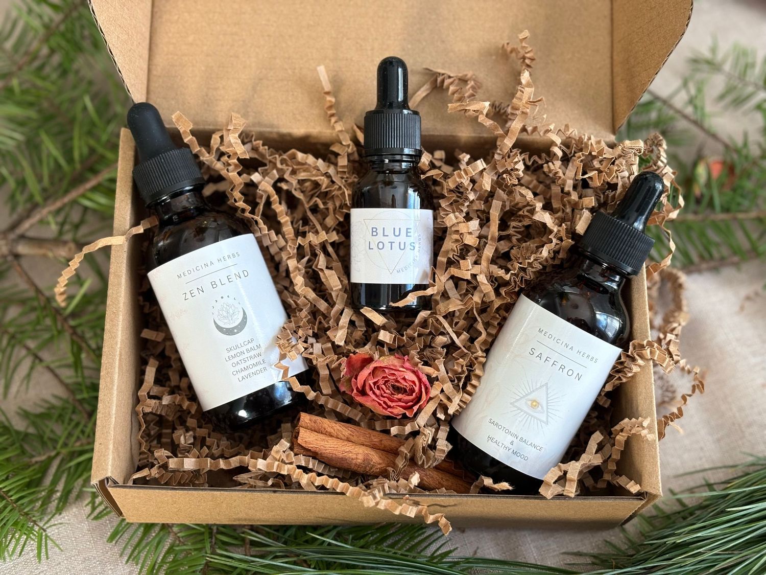 A gift box with three dark glass dropper bottles labeled Yin Blend, Blue Lotus, and another, nestled in kraft paper.
