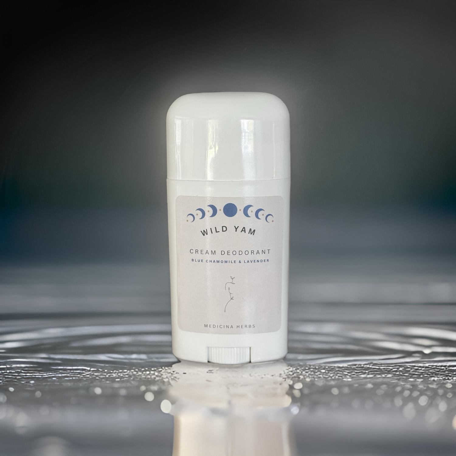 Wild Yam cream deodorant stick in white packaging with moon phase design, displayed on a reflective wet surface.