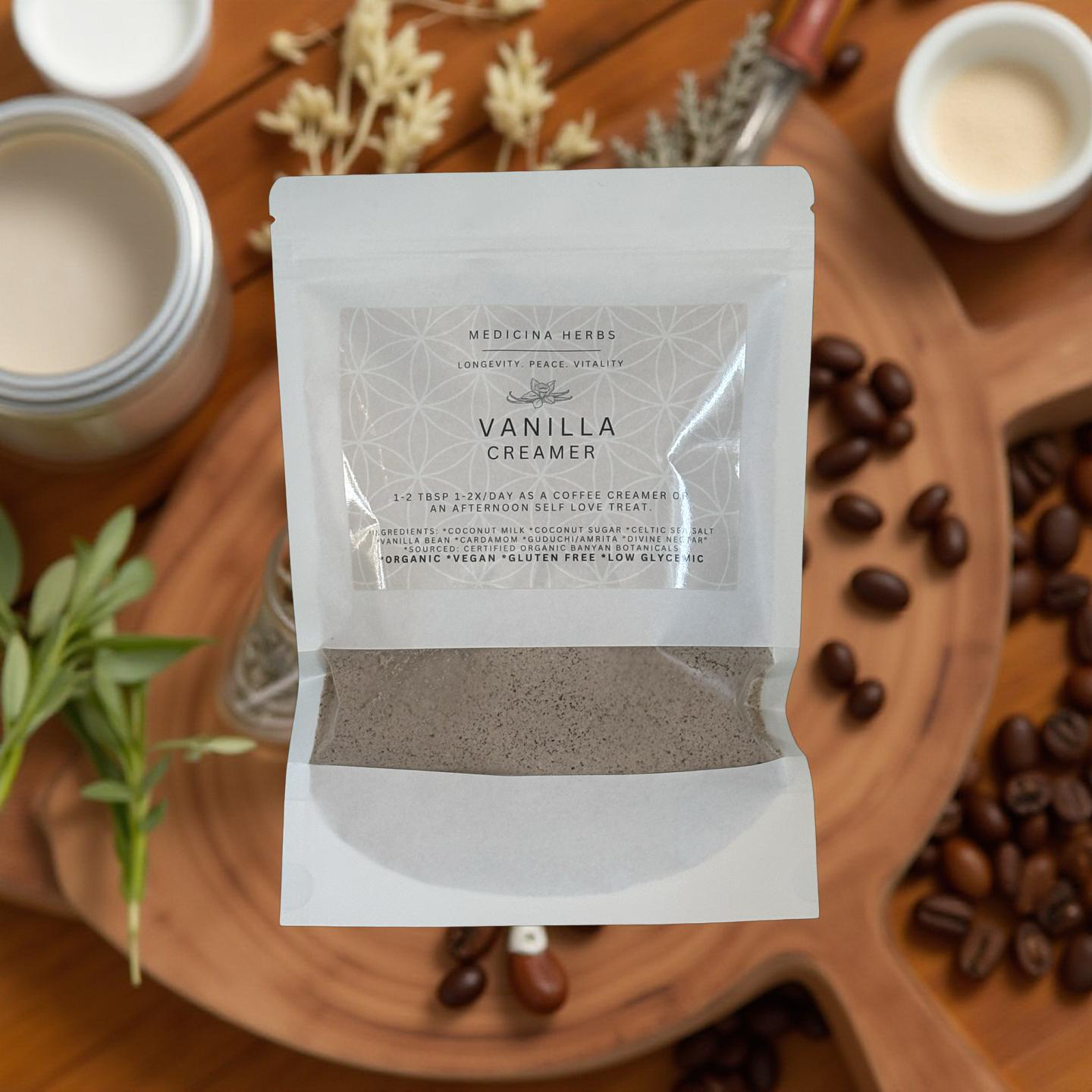 Medicina Herbs Vanilla Creamer packet on wooden board surrounded by coffee beans, herbs, and cream in a cozy flat lay.