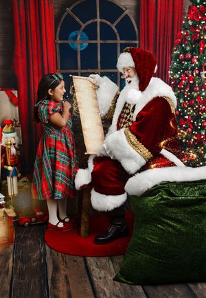 A young girl in plaid dress reads Santa's list with Santa Claus beside a decorated Christmas tree.