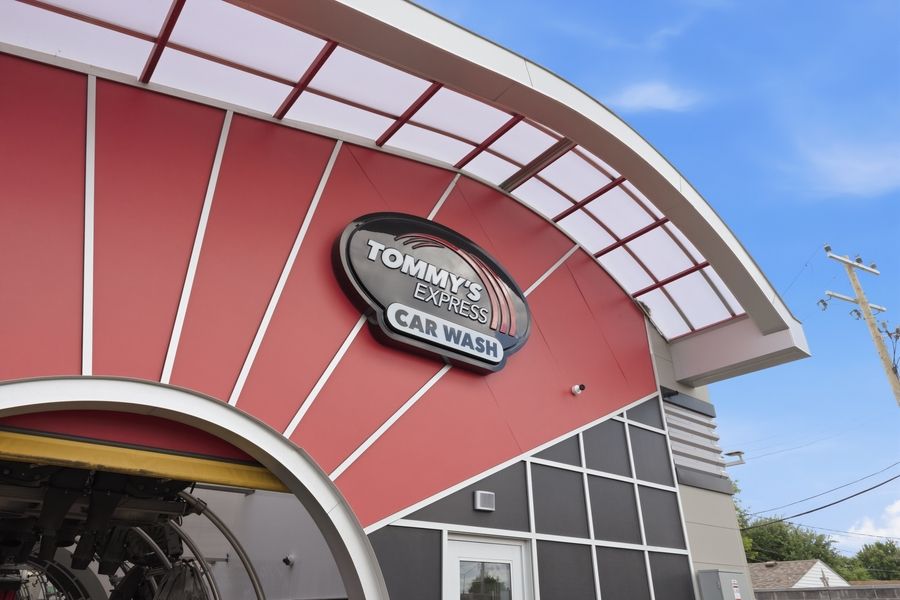 Tommy's Express Car Wash exterior featuring bold red and gray curved architecture with illuminated signage.