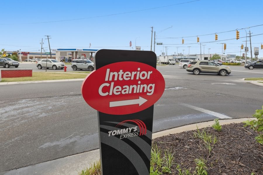 Tommy's Express Car Wash interior cleaning sign at a busy intersection with traffic lights and commercial buildings.
