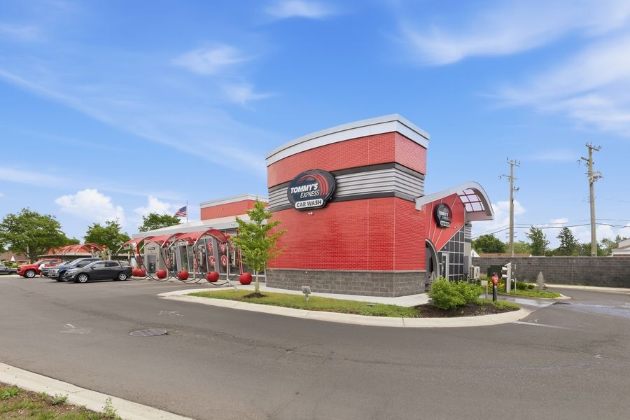 Exterior view of a red car wash facility with circular signage and parking lot.