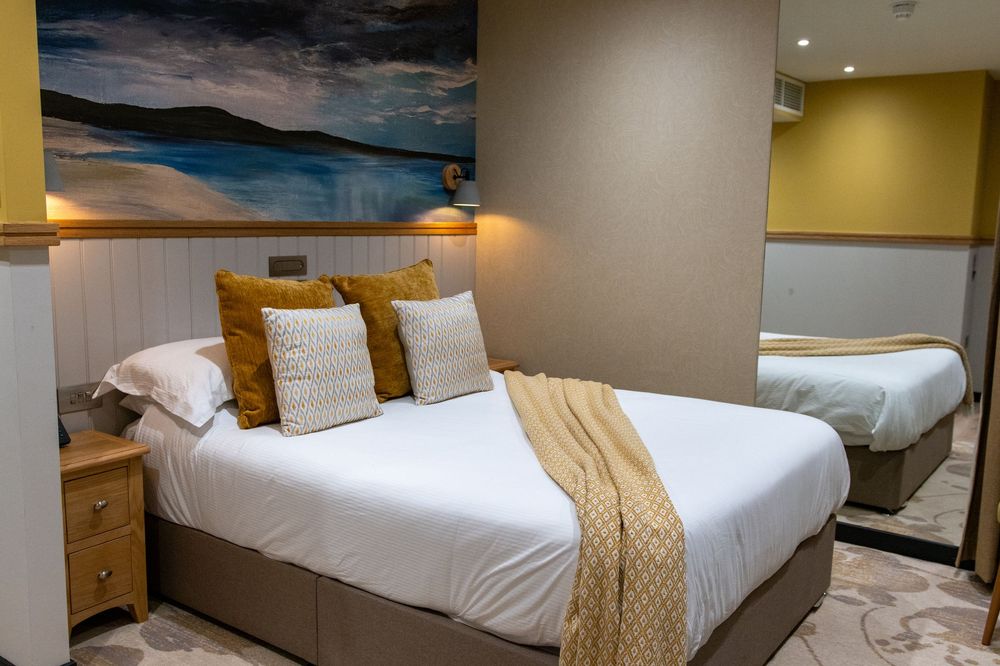Modern hotel room interior with white bedding, wooden furniture, and warm lighting creating a cozy atmosphere.