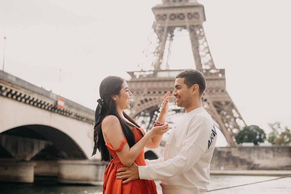 Romantic couple smiling and sharing a tender moment in front of the Eiffel Tower in Paris.