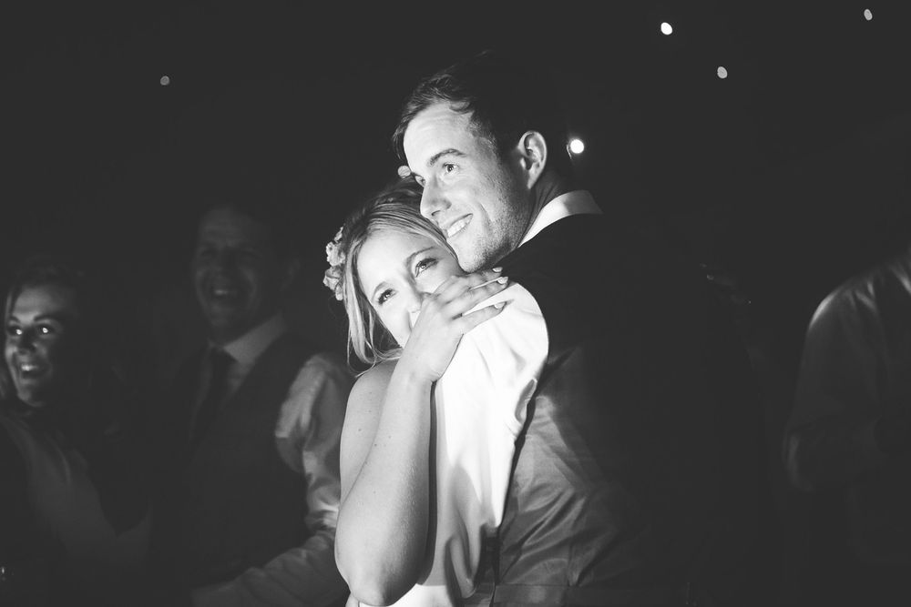 Black and white photo of a couple sharing a tender embrace on a wedding dance floor.