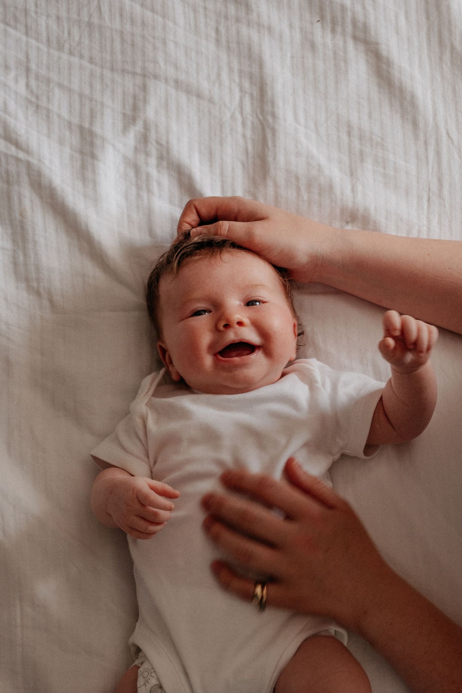 Newborn baby giggling with mums hands on her belly at photoshoot in Monkseaton