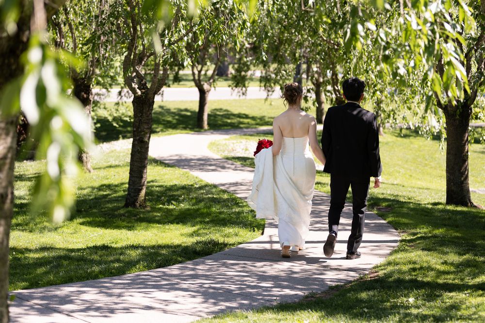Bride & groom walking hand in hand along a garden path surrounded by greenery at the civic garden complex in london, ontario.
