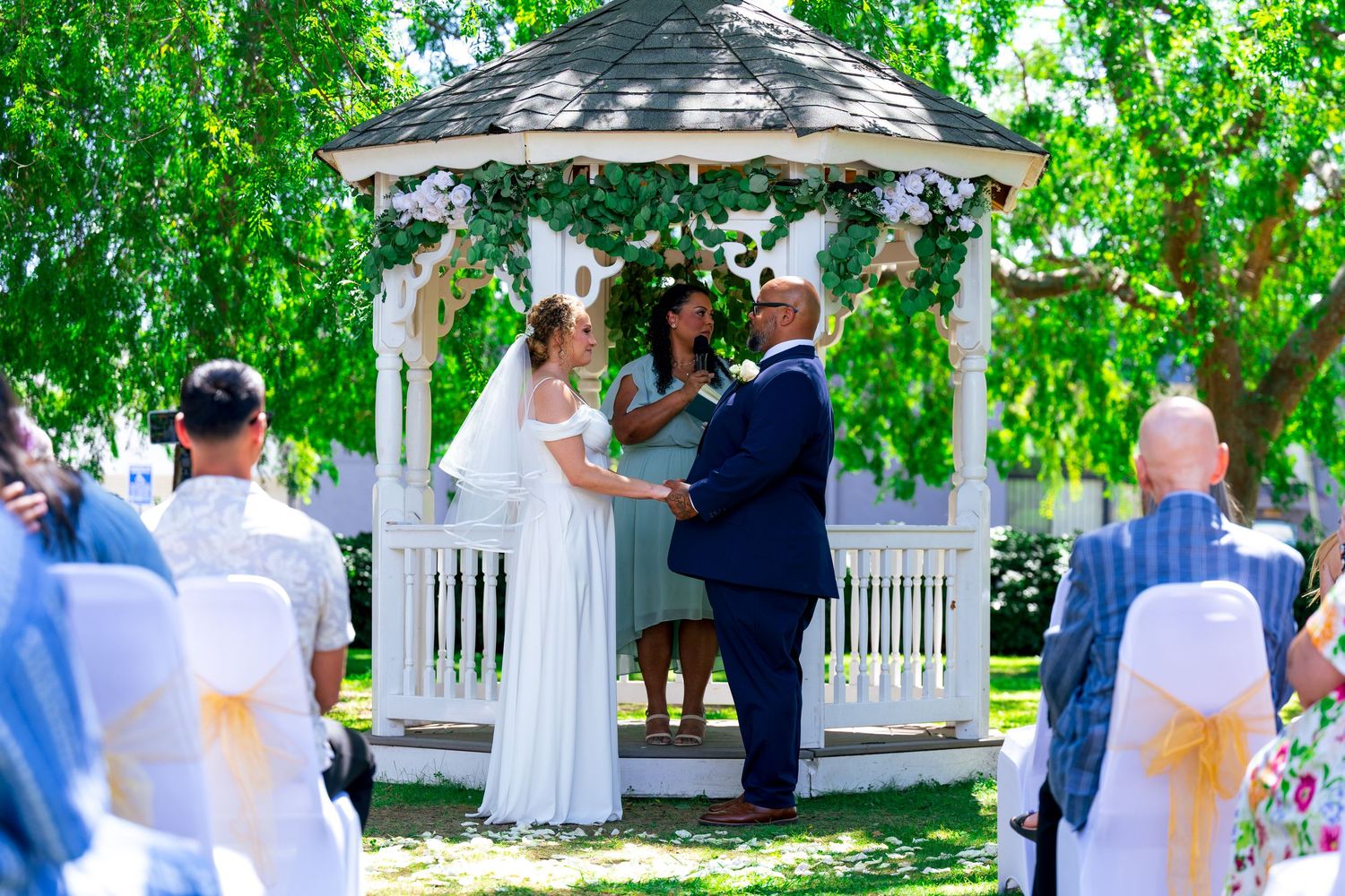 A wedding photo of the bride and groom holding hands at the altar during their garden themed wedding ceremony in LA.
