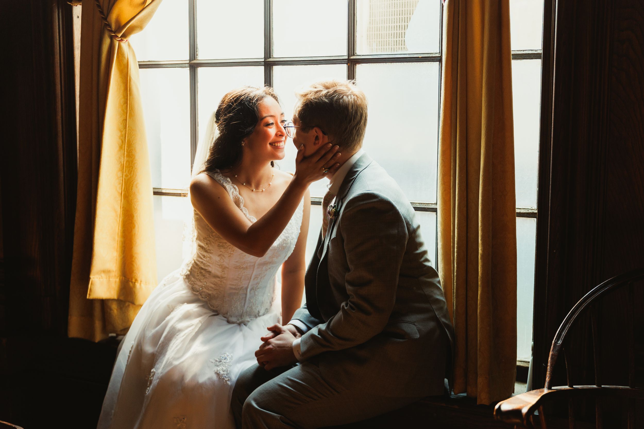 Intimate moment by window with sunlight streaming through yellow curtains.