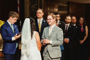 Wedding ceremony in progress with couple exchanging vows while guests look on.