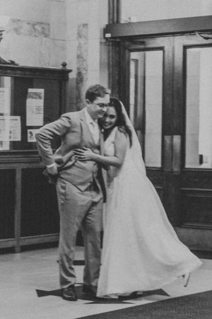 A black and white photo captures a candid moment between newlyweds in a vintage setting.