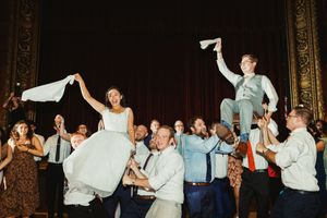 Wedding guests lift and celebrate with the newlyweds during a lively reception dance.