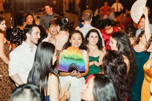 Lively wedding party guests dancing and celebrating with decorative fans.