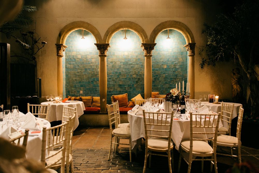 Elegant indoor dining room with arched stone walls, chiavari chairs, and candlelit tables set for a formal event.