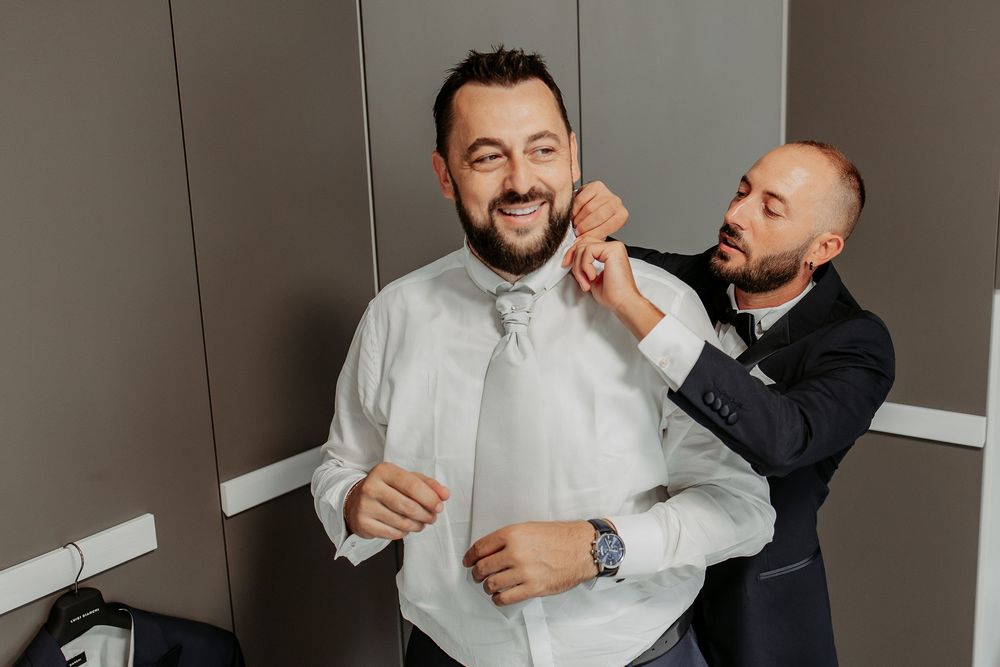 Una persona aiuta Antonio a sistemare il papillon durante i preparativi.