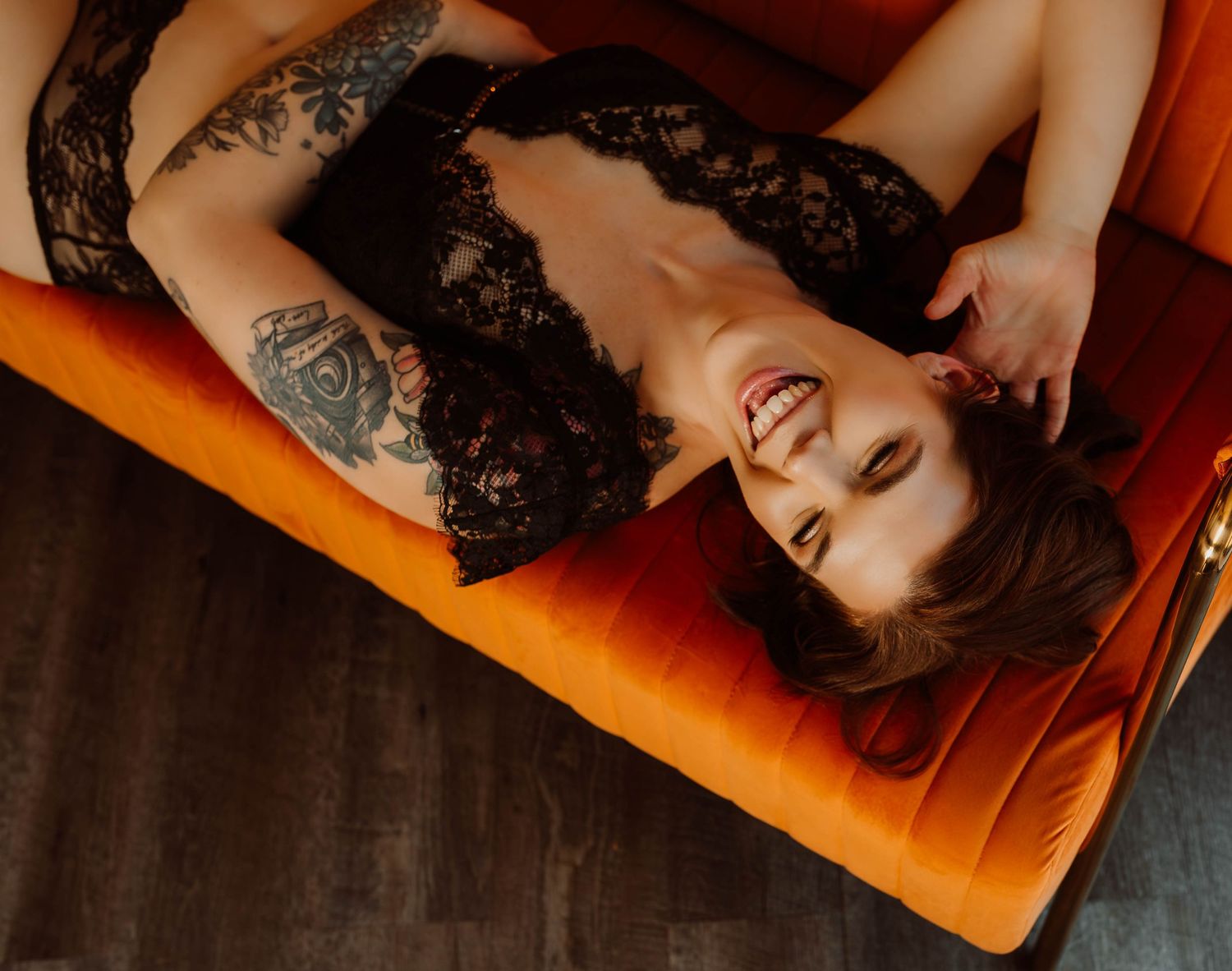 Woman relaxing on a orange couch during a boudoir photography session in Hudson, Wisconsin.