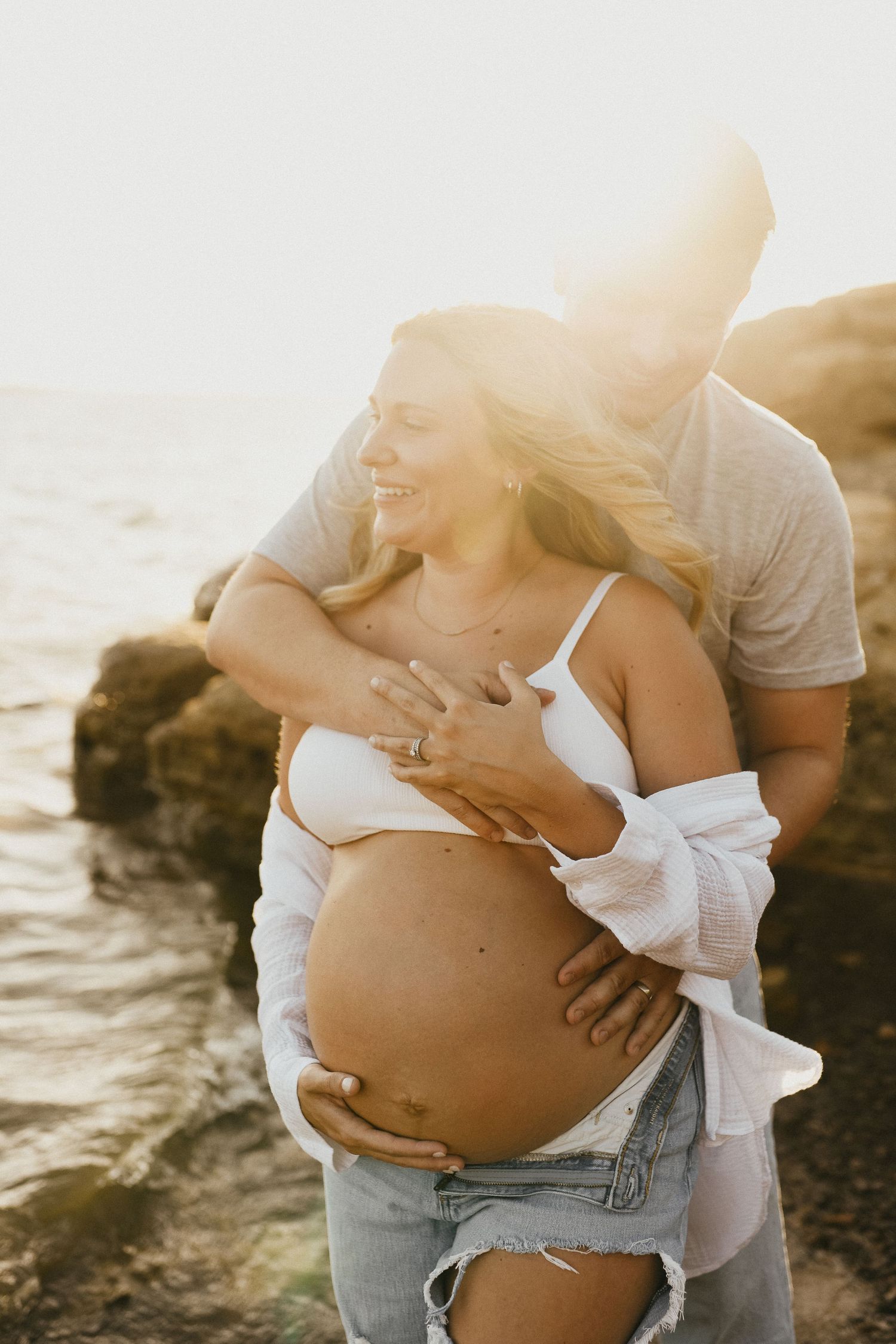 Windblown maternity portrait of an expecting mother beside Lake Grapevine at sunset