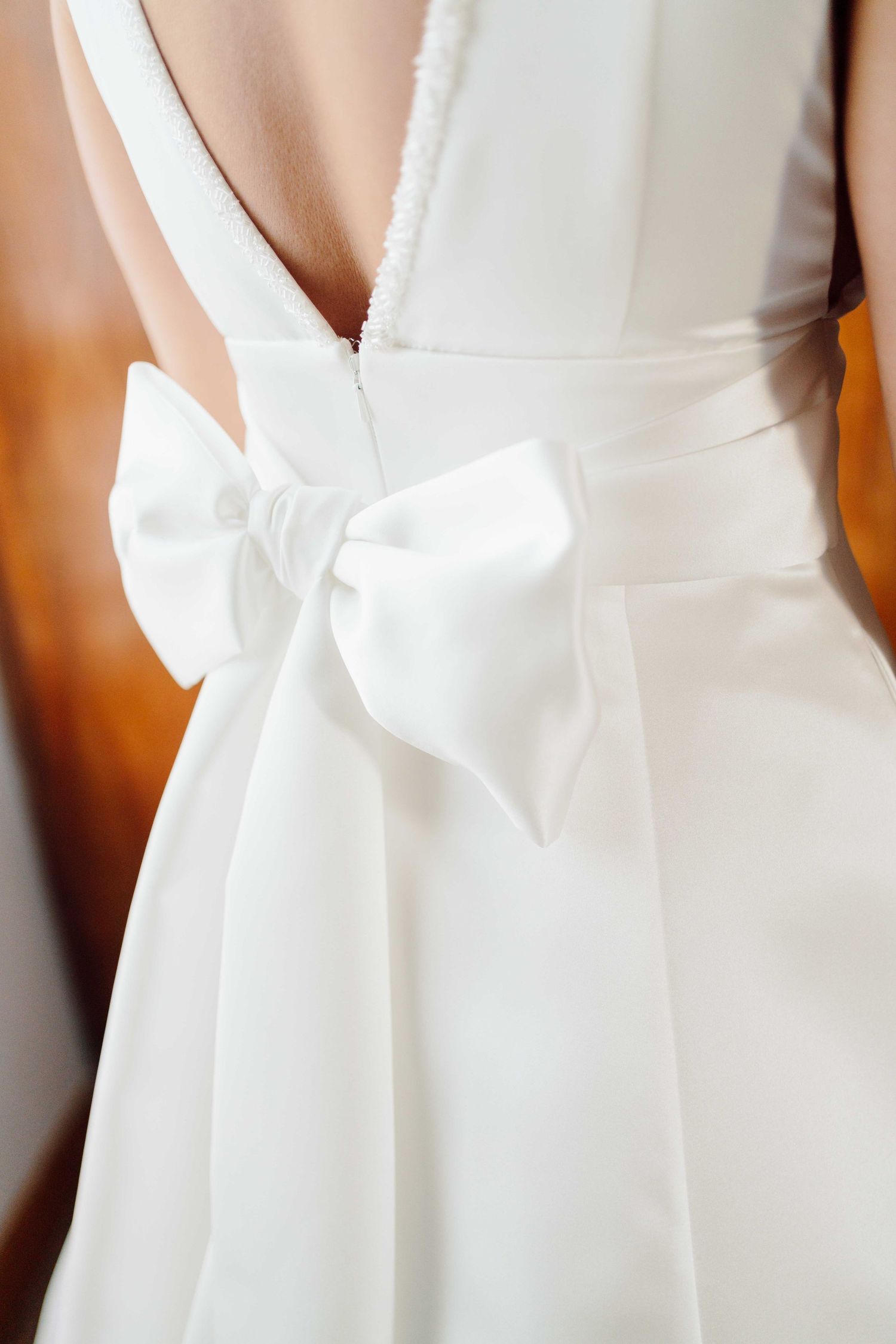 Close-up of a white wedding dress back featuring an elegant satin bow and low open back design.